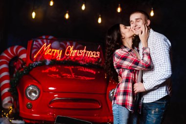 Parlayan ışıkların ve retro arabanın arka planında birbirine sarılan güzel bir çift. Stüdyo fotoğrafı. Sevgililer Günü. Sevgi dolu bir çift. Sevgililer Günü. Noel tatili.