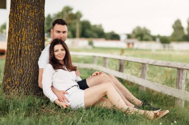 Güneşli bir günde parkta ağaçların altında dinlenen genç bir çift. Aşık mutlu çift dışarıda birlikte vakit geçiriyor. Yakışıklı bir adam ve güzel bir kız yeşil çimenlerde oturmuş ağaca yaslanıyorlar..