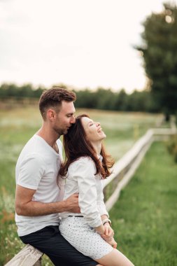 Güzel genç bir çift sıcak bir yaz gününde parkta sarılıp eğleniyor..