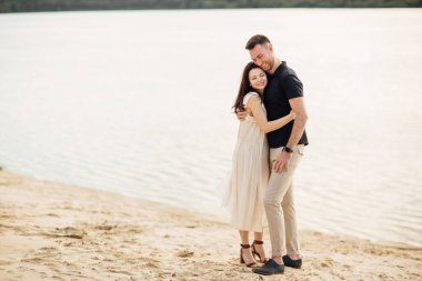 Romantik çift dışarıda kucaklaşıyor. Zarif ve şık bir kadın ve aşık bir adam göl boyunca yürüyorlar. Birlikte mutlu anlar. Aşk hikayesi.