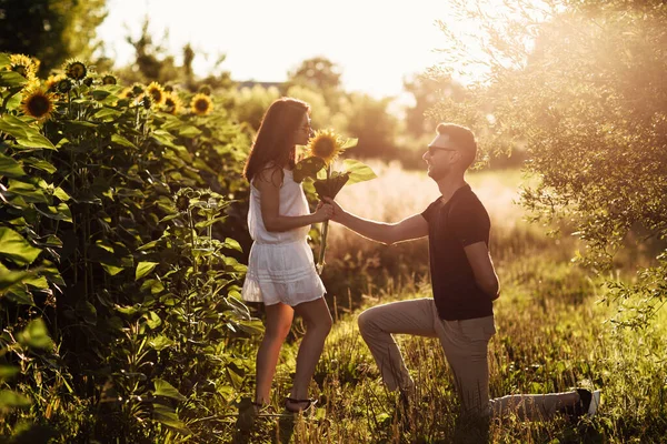 Beautiful couple having fun in sunflowers field. A man and a woman in love walk in a field with sunflowers, a man hugs a woman. selective focus.