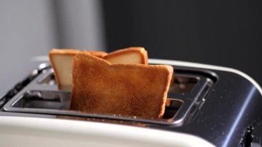 Beyaz tost makinesinde iki dilim kızarmış ekmek. Lezzetli ve kızarmış tost. Kızartma işlemi.