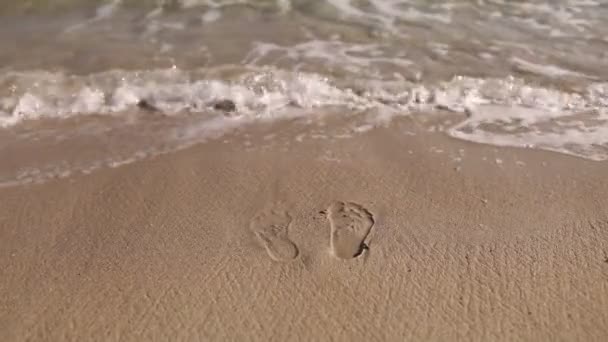 Fußabdrücke im Sand. Das Meer spült Fußspuren im Sand weg. — Stockvideo