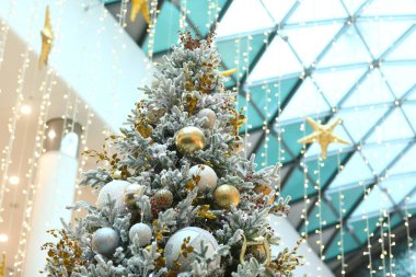 Alışveriş merkezindeki Noel ağacı aşağıdan yukarıya doğru fotoğraflanacak. Görünür çelenkler, dekorasyonlar ve ışık topları, ağacın tepesine çıktı..