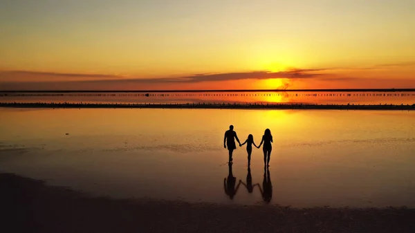三张照片 妈妈和小女儿 在红橙的夕阳西下 走过湖面的浅滩 — 图库照片