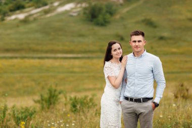 Genç ve güzel bir çift yazın tarlada sarılıyor. Uzun saçlı bir kadın ve şık saçlı bir erkek..