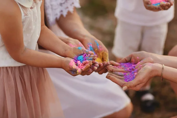 hands of children and adults in the colors of the hall. family having fun with holi paints outdoors. Holi color festival.