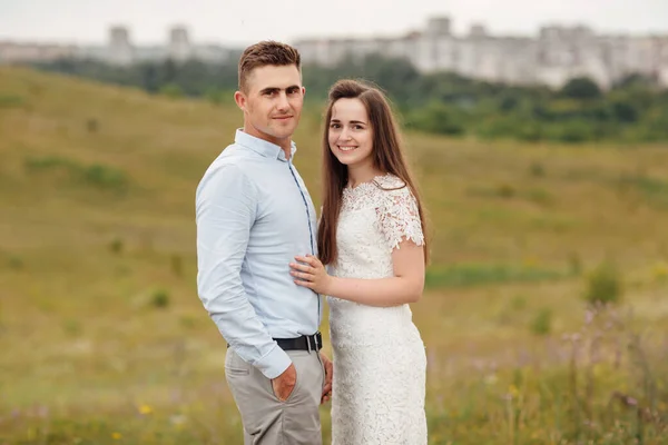 若い美しいカップルは夏に畑で抱き合っています ヘアスタイルの男と長い髪の女 — ストック写真