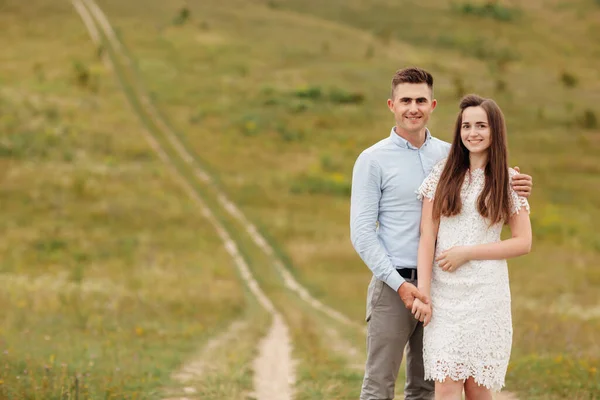 若い美しいカップルは夏に畑で抱き合っています ヘアスタイルの男と長い髪の女 — ストック写真