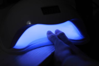 Jöle cilası manikürlü kadın ellerinin yakın görüntüsü. Tırnak cilasının üst kapağını iyileştirmek için kadın el fenerine elini sokuyor. UV lambası, LED çivi.