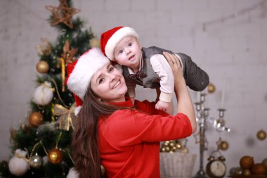 Genç, çekici, mutlu anne oğluyla Noel ağacının yanında iyi vakit geçiriyor. Aile, mutluluk, tatiller, yeni yıl konsepti