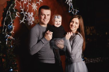 Şirin, genç bir aile babası, anne ve bebek Noel arka planında sarılıp öpüşüyorlar. Mutlu Noeller ve mutlu yıllar.