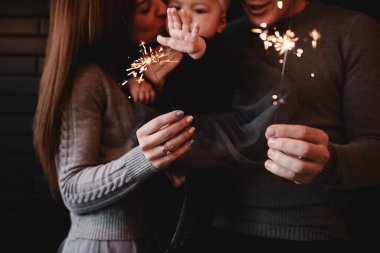 Mutlu aile portresi, anne, baba ve bebek maytap ve ışık ile. Noel 'i bekleyen bir aile. seçici fotoğraf