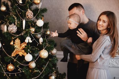 Mutlu aile Noel ağacını süslüyor. Aile yeni yıla hazırlanıyor..