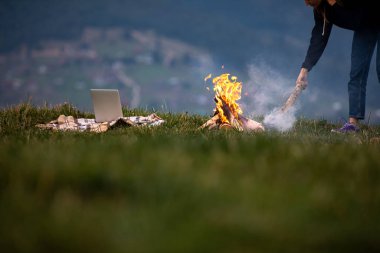 Genç serbest çalışan kadın akşamları dağlarda ateşe odun atıyor. Turist kız dinleniyor ve dışarıda çalışıyor..