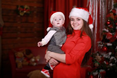 Genç, çekici, mutlu anne oğluyla Noel ağacının yanında iyi vakit geçiriyor. Aile, mutluluk, tatiller, yeni yıl konsepti