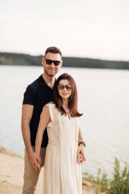 Romantik çift dışarıda kucaklaşıyor. Zarif ve şık bir kadın ve aşık bir adam göl boyunca yürüyorlar. Birlikte mutlu anlar. Aşk hikayesi.