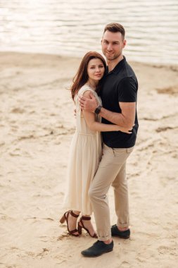 Romantik çift dışarıda kucaklaşıyor. Zarif ve şık bir kadın ve aşık bir adam göl boyunca yürüyorlar. Birlikte mutlu anlar. Aşk hikayesi.