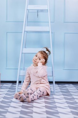 Tek boynuzlu at kostümlü güzel küçük bir kız gülümsüyor ve mavi duvarda eğleniyor. Mutlu çocukluk