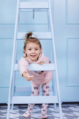 Tek boynuzlu at kostümlü güzel küçük bir kız gülümsüyor ve mavi duvarda eğleniyor. Mutlu çocukluk