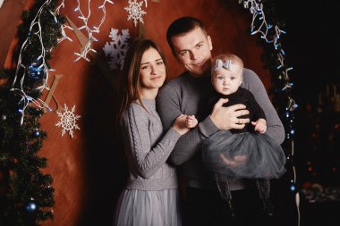 Şirin, genç bir aile babası, anne ve bebek Noel arka planında sarılıp öpüşüyorlar. Mutlu Noeller ve mutlu yıllar.