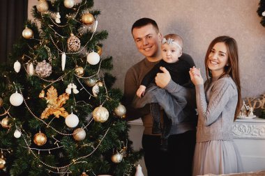 Mutlu aile Noel ağacını süslüyor. Aile yeni yıla hazırlanıyor..