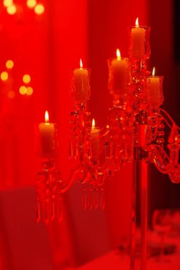 Kırmızı ışıkta yanan mumlar ve kristal olan şenlikli düğün masası. Kristal mum tutacağı bir düğün resepsiyonunda orta parça olarak