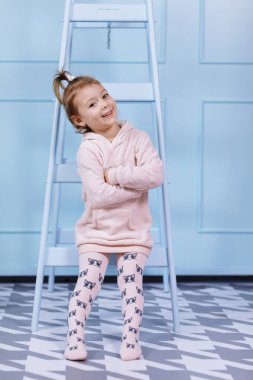 Tek boynuzlu at kostümlü güzel küçük bir kız gülümsüyor ve mavi duvarda eğleniyor. Mutlu çocukluk