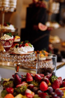 Güzel dekore edilmiş yemek masası. Farklı taze meyveler ve kurumsal doğum günü partisinde tatlı. Ya da düğün kutlamalarında.