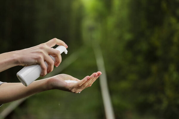 Женская рука использует косметическую бутылку с пеной для чистки. Натуральный органический СПА косметический продукт для тела и лица. продукты по уходу за кожей на зеленом природном фоне. косметический уход за кожей