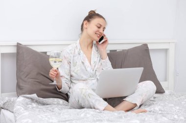 Evde telefonla konuşan ve limonlu su içen bir kız. Kadın çalışıyor, öğreniyor ve yatak odasında dizüstü bilgisayar kullanıyor. Serbest çalışan biri. Yazıyorum, yazıyorum. İletişim ve teknoloji kavramı