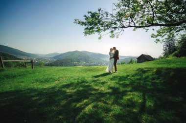 Mutlu şık gelin ve damat yaz güneşli bir günde dağlarda koşup eğleniyor. Muhteşem yeni evli çift gülüyor, gerçek duygular. Duygusal romantik an