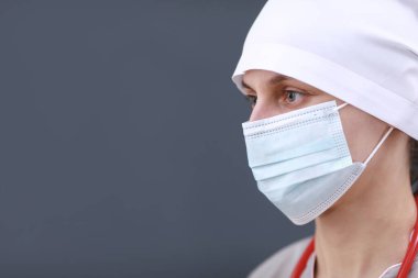 Tıbbi maske ve form takan kadın doktor portresi. Boynunda steteskop var. Gri arka planda izole edilmiş. Sağlık ve Tıp Hizmetleri. Hastalığı önleme kavramı