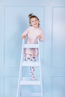 Tek boynuzlu at kostümlü güzel küçük bir kız gülümsüyor ve mavi duvarda eğleniyor. Mutlu çocukluk