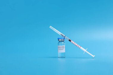 Coronavirus aşısı olan ilaç şişesi covid-19. Aşı için tıbbi cam şişe ve şırınga. mavi arka planda izole edilmiş laboratuvar, hastane veya eczane konseptinde sıvı aşı.