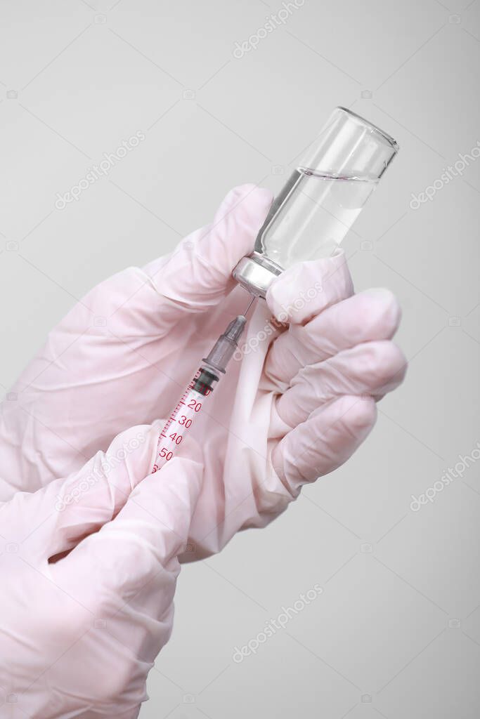 Doctor, nurse or scientist hand in white medical gloves holding flu, measles, coronavirus vaccine shot for diseases outbreak vaccination, medicine and drug concept.
