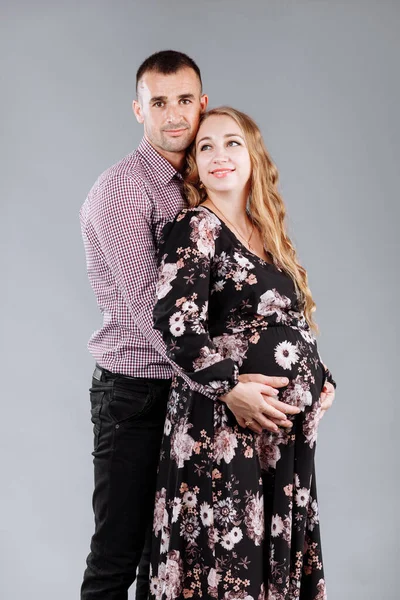 Gravid Kvinna Och Hennes Man Kramas Grå Bakgrund Studion — Stockfoto