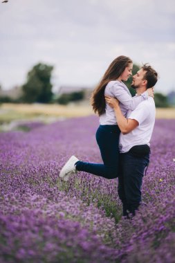 Genç çift yaz günü lavanta tarlasında eğleniyor. Aşk hikayesi. Kadın ve erkek dışarıda yürüyorlar..