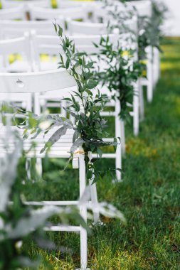 Bir düğün töreninde süslü beyaz sandalyeler..