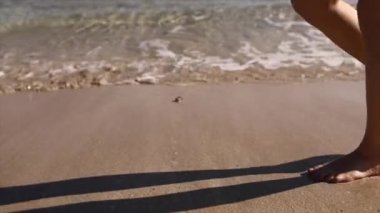 Denizin kumlu sahillerinde çıplak ayakla yürüyen bir kadın.