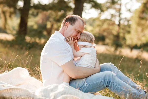 Father playing with baby girl in the park in nature on summer holiday. Portrait dad with child together on picnic. Daddy is hugging his little daughter outdoors. Family holiday. father\'s, baby\'s day