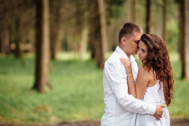 Birbirine aşık genç bir çift güneşli bir günde bir yaz parkında sarılıyorlar. Dışarı çık, iyi giyimli, çok heyecanlı ve sevimli..