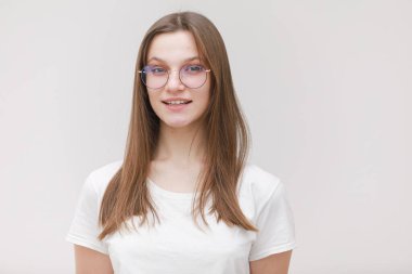 Gözlüklü genç kız kameraya bakıp gülümsüyor. Gözlüklü güzel kadın model beyaz arka planda izole edilmiş bir poz veriyor..