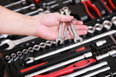 Alet deposu. Erkek el ele tutuşan anahtarlar. Alet kutusunda otomatik tamir seti var. Tamirci aletleri ayarlandı. Alet çantasının içinde siyah kırmızı anahtarlar, fünyeler ve farklı hortumlar var. Yakın çekim.