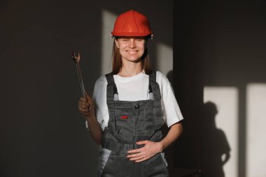 Güzel inşaat işçilerinin portresi koruyucu giysiler, turuncu miğfer, ingiliz anahtarı, güneş ışığı olan büyük vida anahtarı..