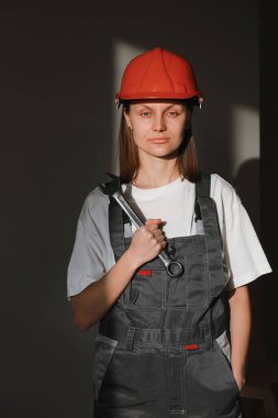 Güzel inşaat işçilerinin portresi koruyucu giysiler, turuncu miğfer, ingiliz anahtarı, güneş ışığı olan büyük vida anahtarı..