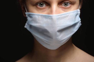 Coronavirus hastalığı COVID-19 salgını sırasında koruyucu maske takan genç bir kadın. Stüdyo resmini siyah bir arkaplanda kapat