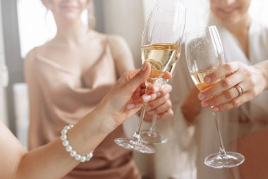 Gelinin sabahı. En iyi nedimeleri olan muhteşem gelin elinde bardak, pencerenin yanındaki otel banyosunda şampanya içiyor. Heyecan verici gecelikli seksi nedimeler. Düğün sabahı detayları.