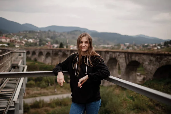 Young woman standing near old viaduct. Tourist girl in scenery countryside by the Historical abandoned railway arch bridge viaduct in Vorokhta, Ivano-Frankivsk Region, Ukraine.