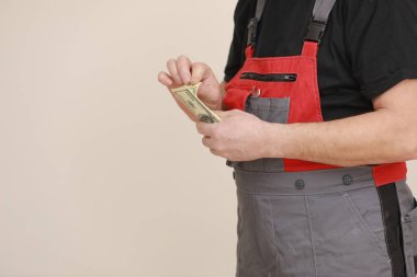 Tulumlu ve koruyucu maskeli bir inşaatçı, inşaat alanında yaptığı iş için maaşını transfer ediyor. Paraya odaklı yakın plan görüntüsü.